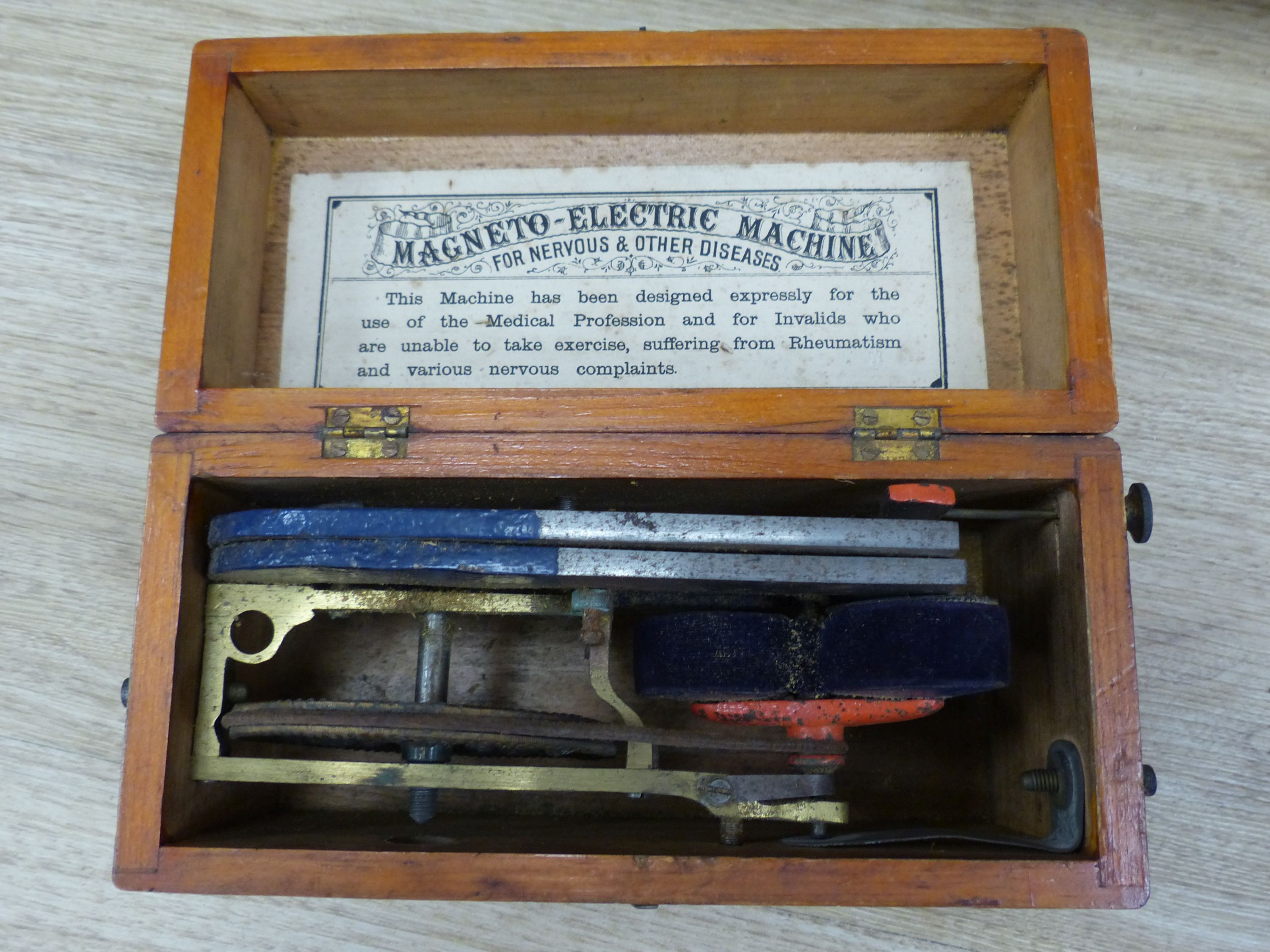 A leather cabinet case containing doctors equipment, a circular plated container, a wooden case and a magneto electric machine